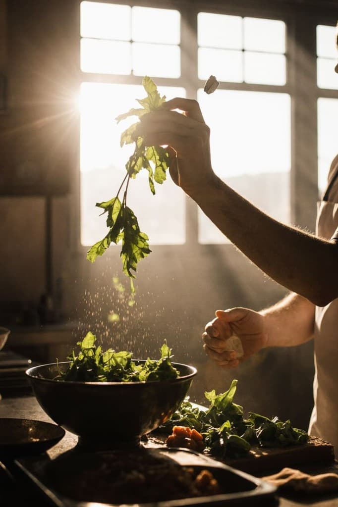 Fresh greens and herbs prepared in a sunlit kitchen